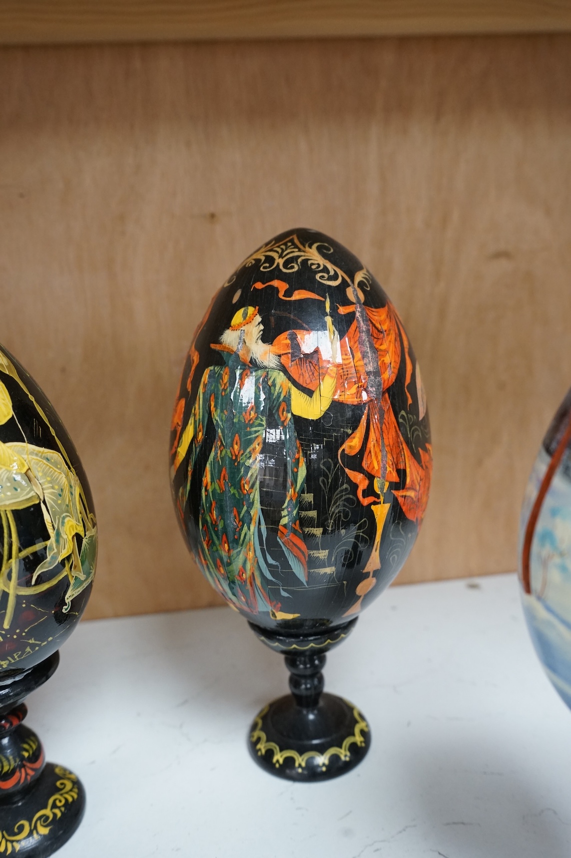 Five Russian painted and lacquered 'eggs' on stands, one inscribed in cyrillic, largest 21cm high